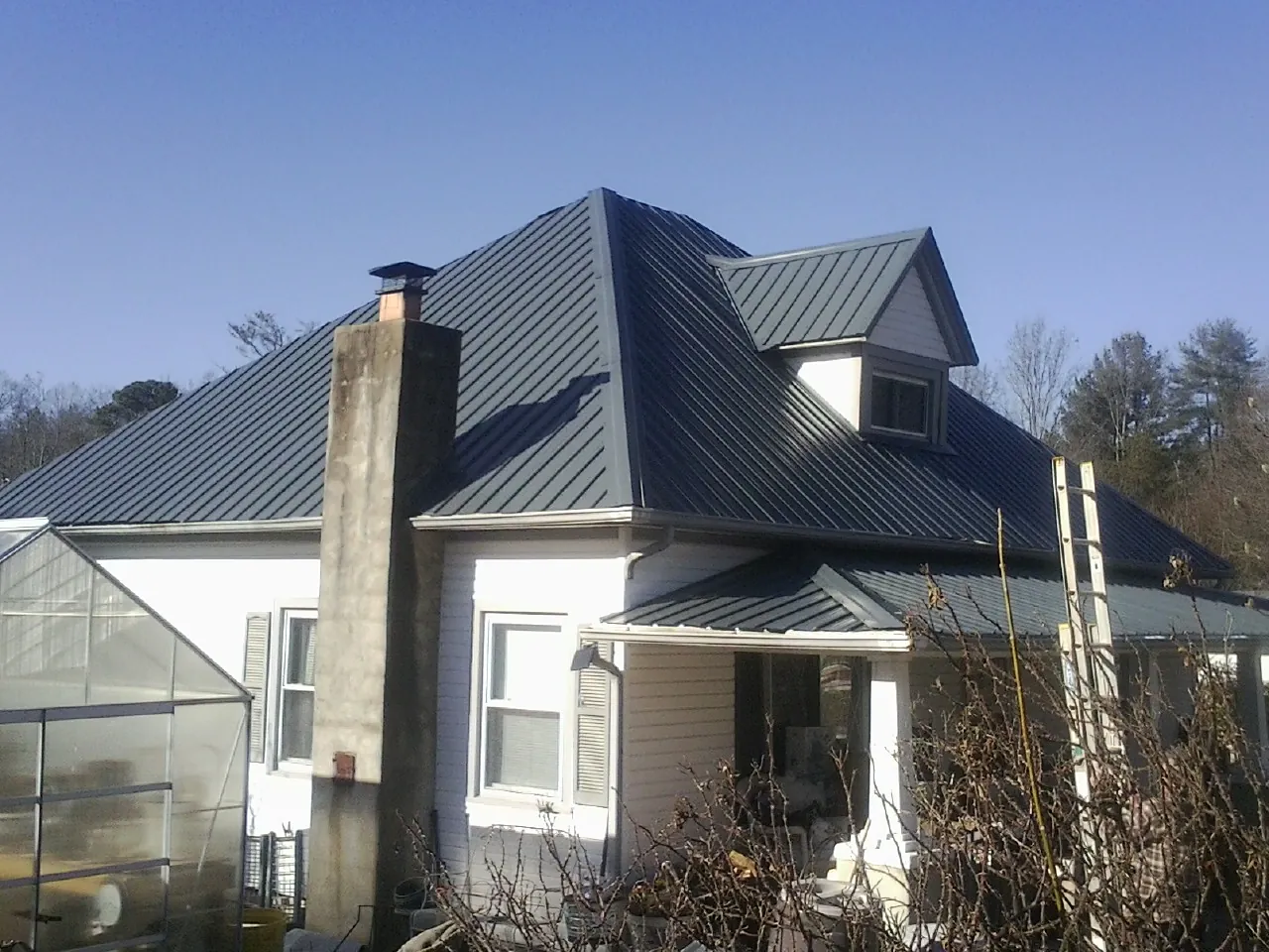 Dark blue standing seam metal roof on a white farmhouse with dormer — Slate & Tile Roof Repair by Roofing Brothers in San Quentin