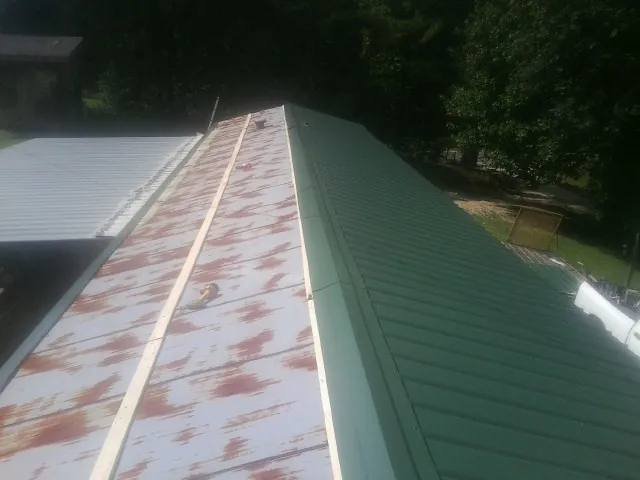 Old rusted panels beside newly installed green metal roofing — Wind Damage Roof Repair by Roofing Brothers in San Quentin