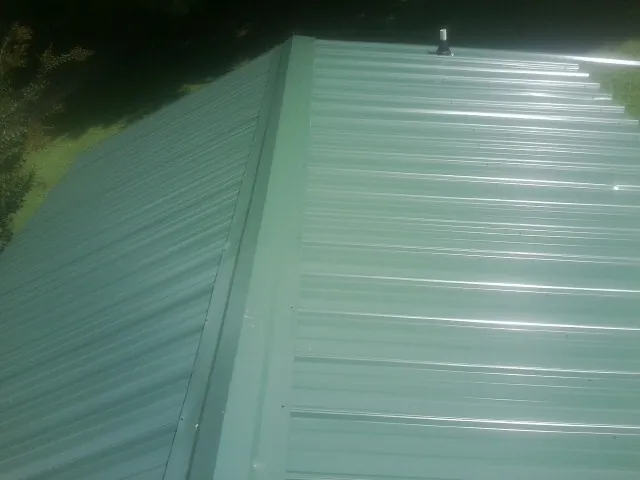 New green metal panels meeting at the ridge of a roof — Flat Roof Repair work by our crew in San Quentin