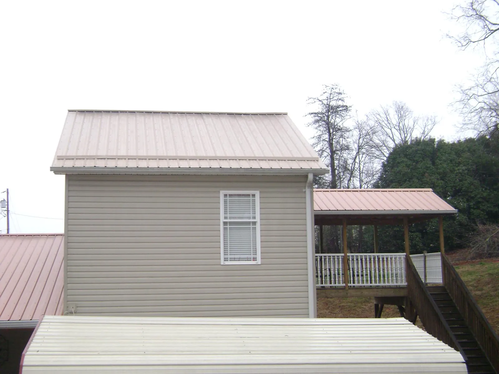 Tan metal roofs on a two story addition and attached porch, from a Roof Replacement job in San Quentin