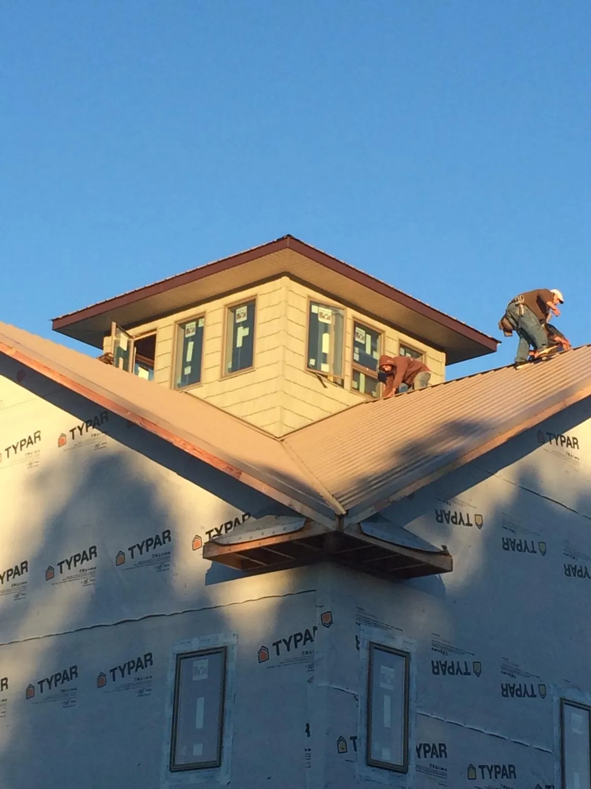 Roofers working around a rooftop cupola on a new metal roof at sunset — Roof Waterproofing in San Quentin by Roofing Brothers